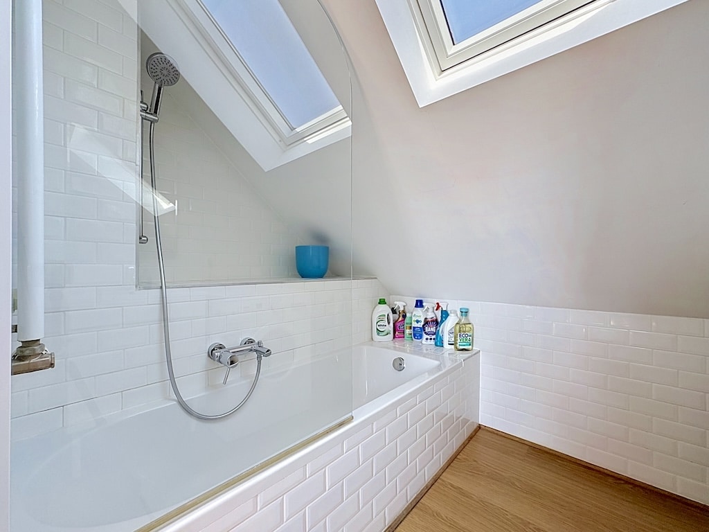 Salle de bain sous toit à Londres avec baignoire, douche vitrée et fenêtres de toit