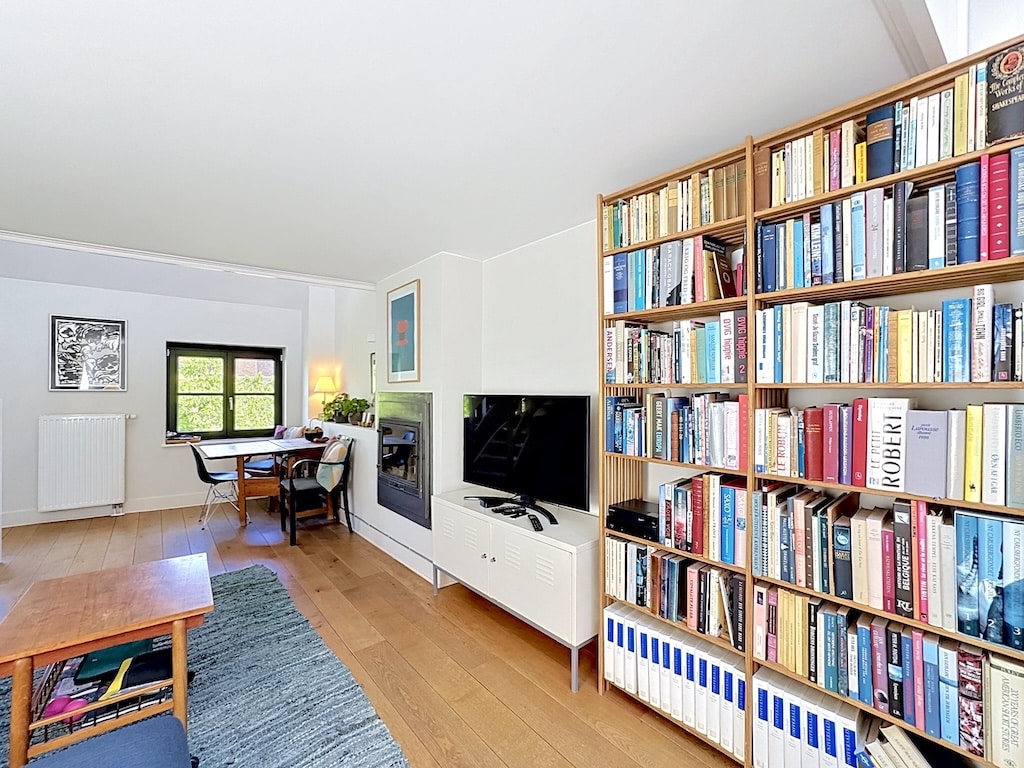 Salon lumineux à Londres avec grande bibliothèque, cheminée moderne et parquet clair