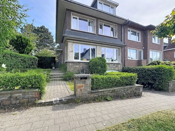 Facade of semi-detached house with landscaped garden and paved driveway
