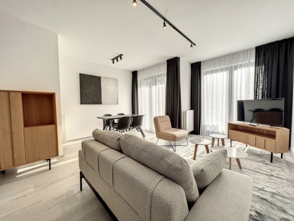 Salon dappartement moderne et lumineux avec canapé gris coin repas et grandes fenêtres   appartement 1 chambre  woluwe saint lambert