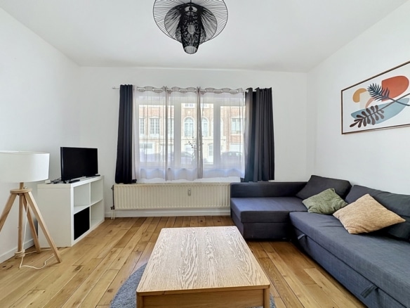 Salon contemporain lumineux avec parquet canapé dangle gris et grande fenêtre   appartement 1 chambre  etterbeek