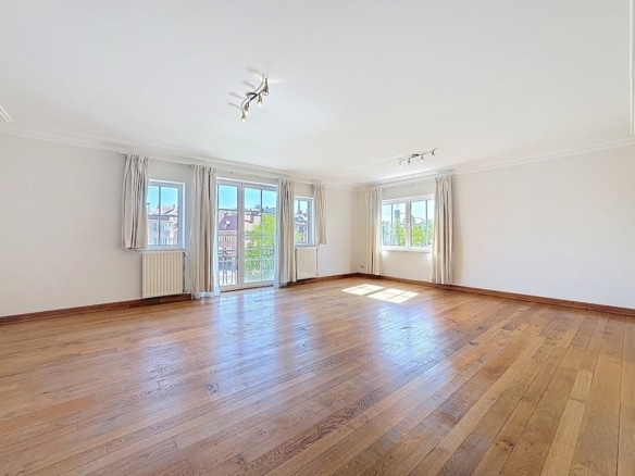 Large, bright living room with parquet floor, large windows and glass door to balcony