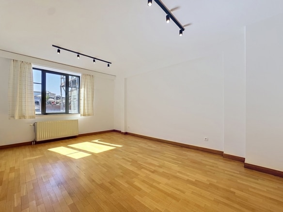 Salon lumineux dappartement vide avec parquet grande fenêtre et murs blancs   appartement 1 chambre  bruxelles