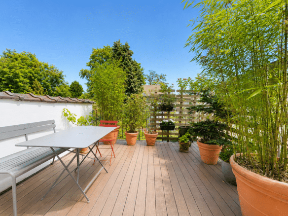 Terrasse en bois ensoleillée avec mobilier de jardin et plantes luxuriantes   appartement avec terrasse  espace vélo  forest