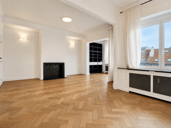 Salon lumineux avec parquet en chevrons cheminée décorative et vue sur les toits   appartement 2 chambres  ixelles