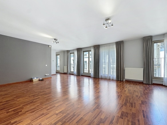 Salon lumineux dappartement avec parquet grandes fenêtres et rideaux gris   appartement 2 chambres  bruxelles