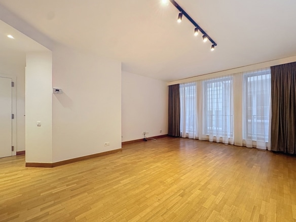 Salon lumineux vide avec parquet grandes fenêtres et rideaux dans appartement moderne   appartement 1 chambre  bruxelles