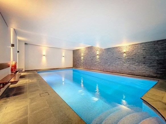 Piscine intérieure luxueuse de maison avec mur en pierre et éclairage chaleureux   appartement 3 chambres  woluwe saint lambert