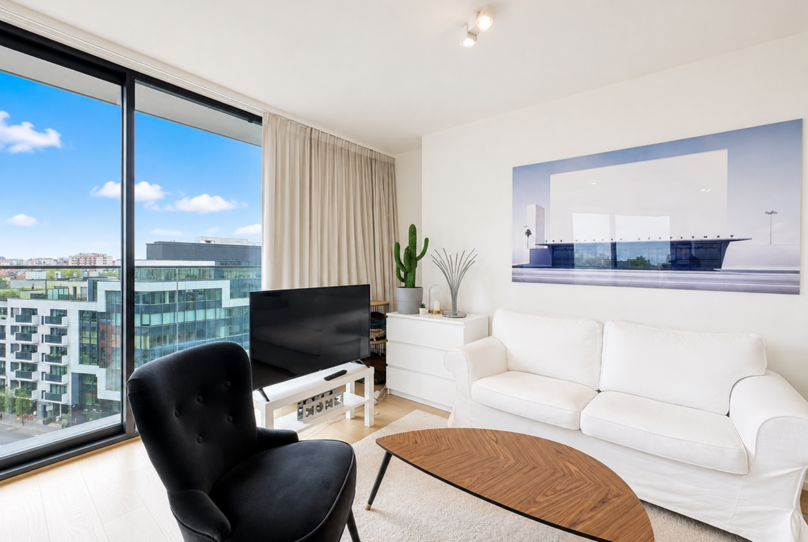 Salon lumineux d’appartement moderne avec vue urbaine et décoration minimaliste.