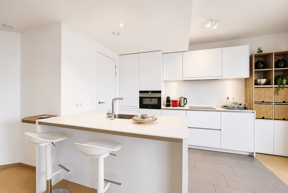 Cuisine moderne blanche avec îlot central dans maison contemporaine.