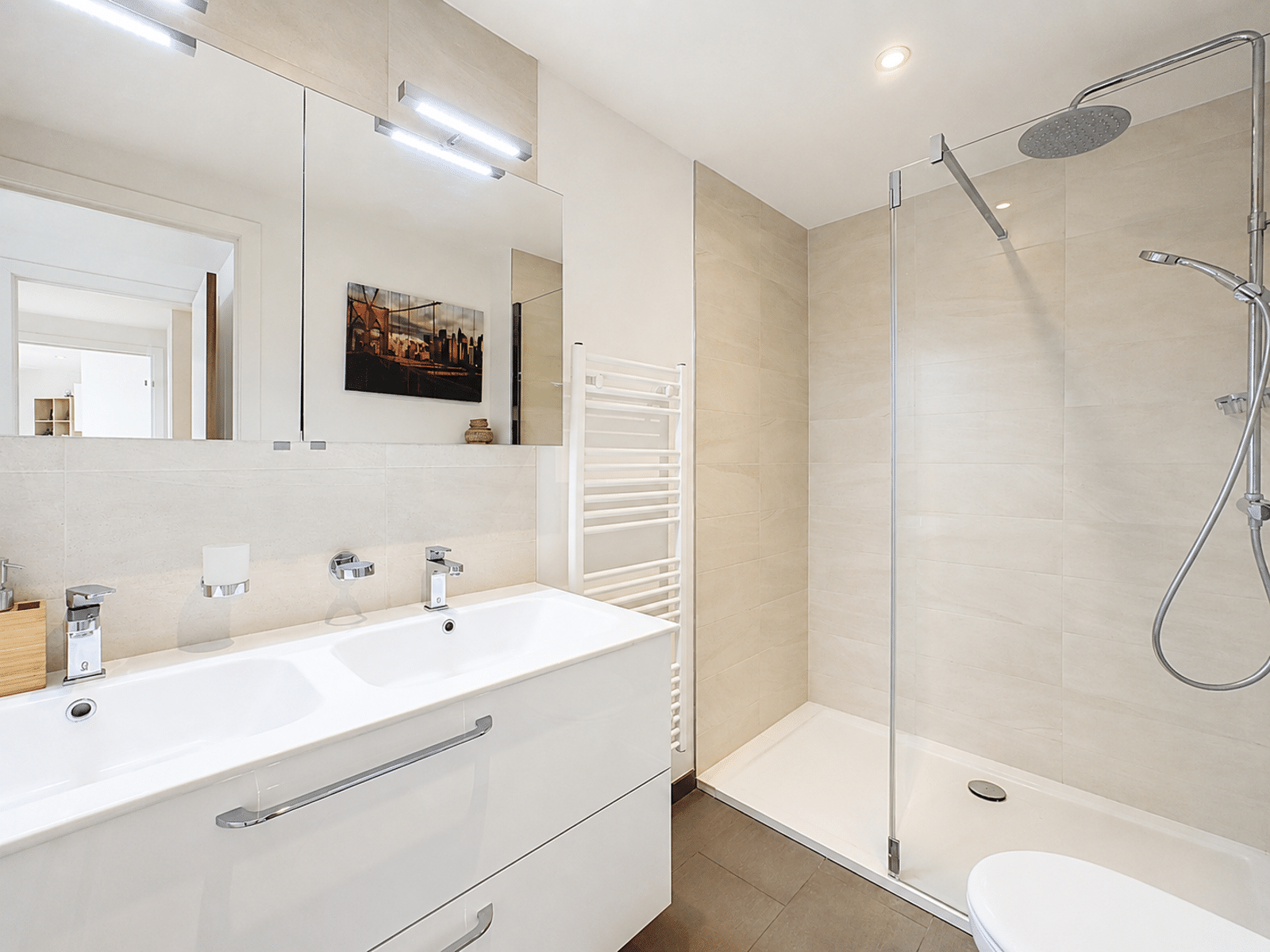 Salle de Bain avec Double Vasque – You Real Estate Agency Modern bathroom with a white double vanity, large mirror, and a glass-enclosed shower with a rainfall head.