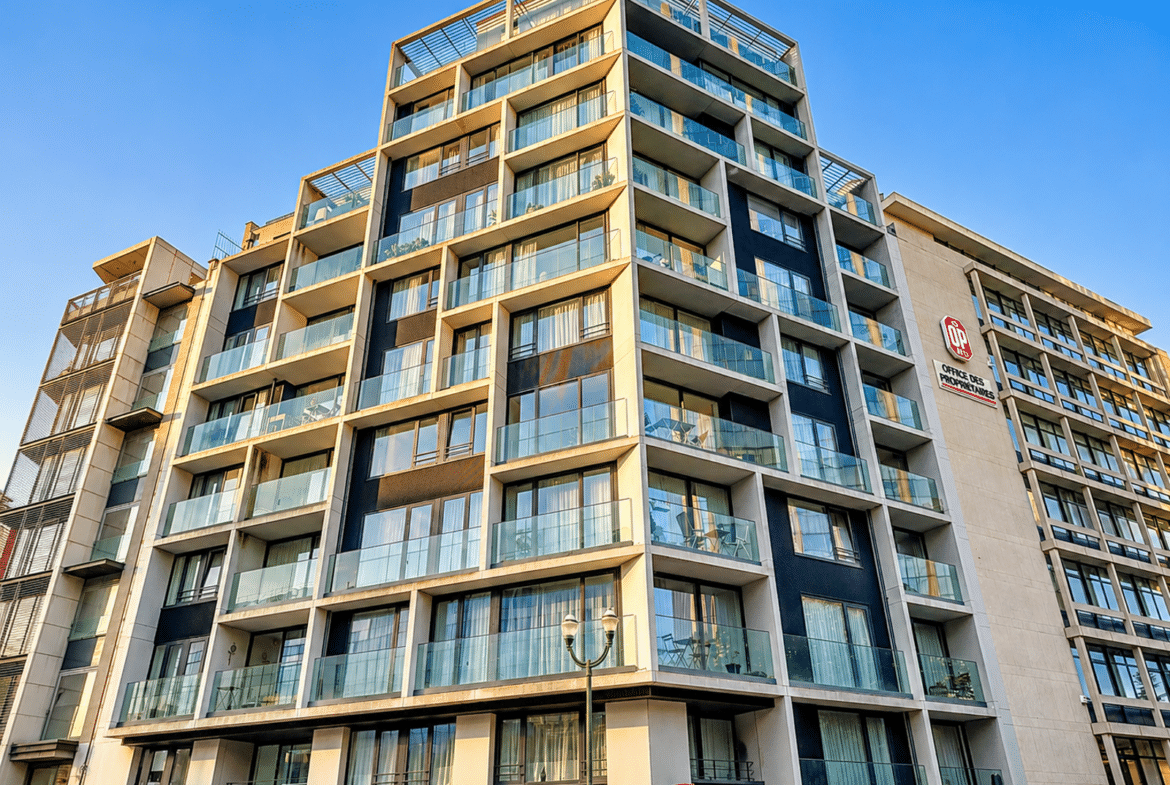 Immeuble d’appartements moderne avec terrasses vitrées et commerces en rez-de-chaussée.