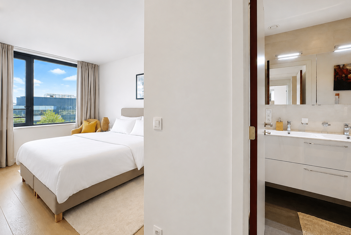 Appartement moderne avec chambre lumineuse et salle de bain attenante.