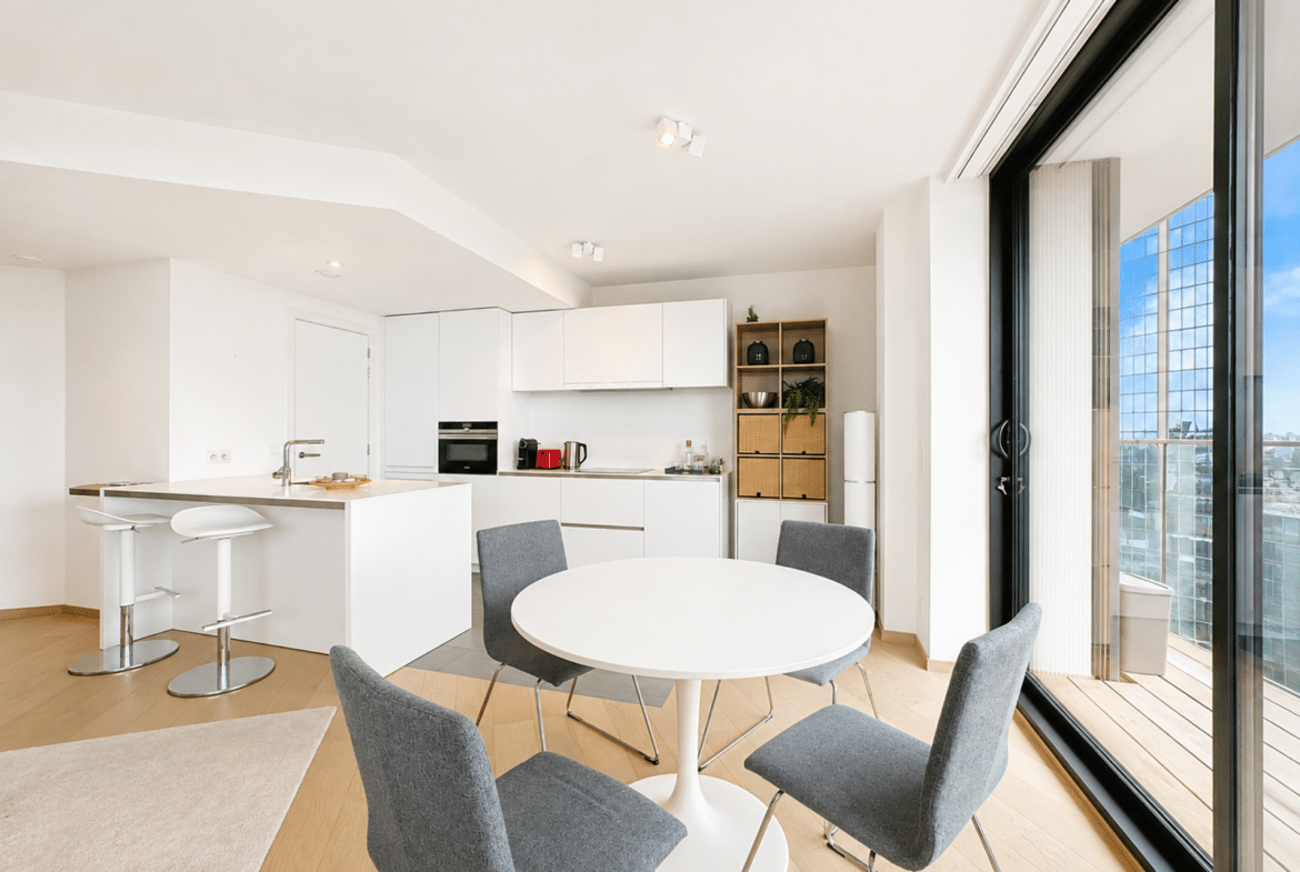 Cuisine ouverte moderne avec coin repas lumineux dans appartement contemporain.