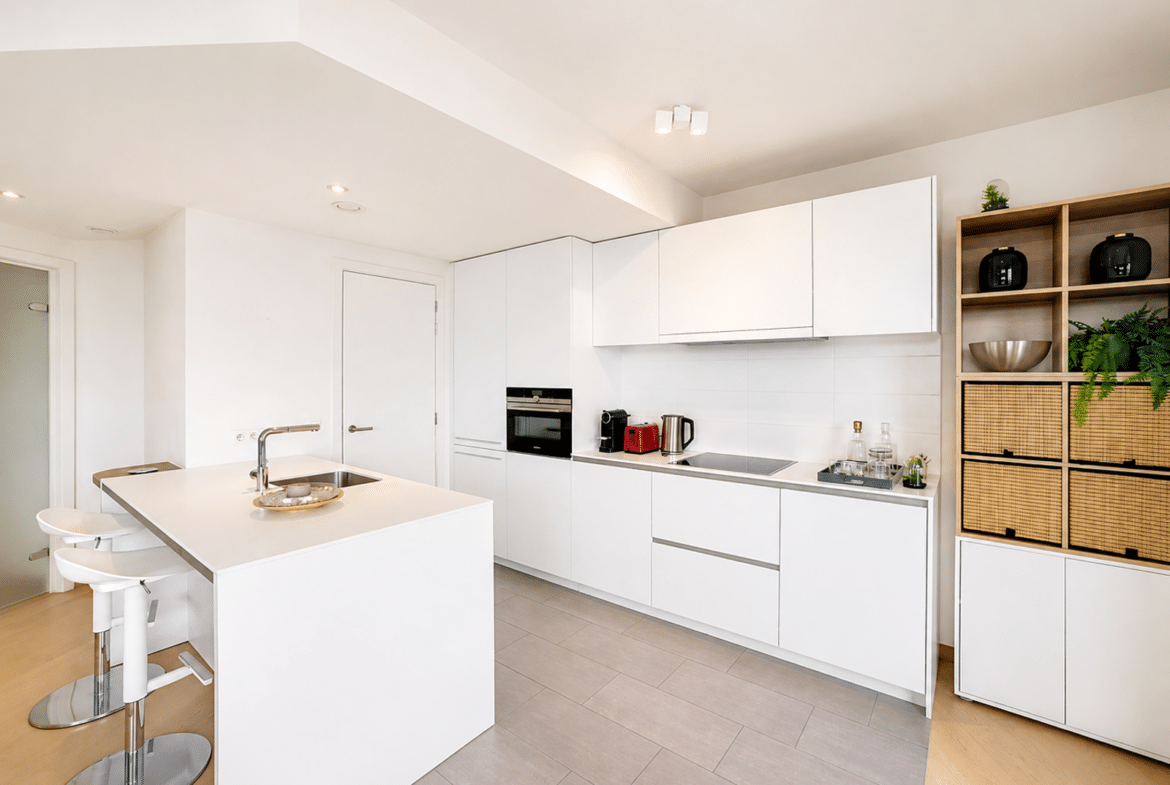 Cuisine moderne blanche avec îlot central et électroménagers intégrés dans une maison contemporaine.
