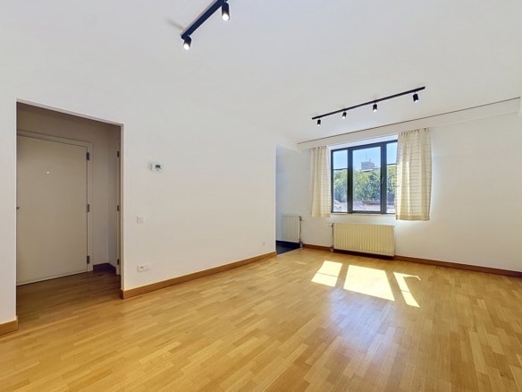 Salon lumineux vide avec parquet bois grande fenêtre et éclairage moderne dans appartement   appartement 1 chambre  bruxelles