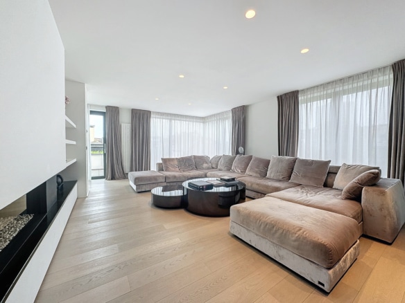 Salon dappartement moderne lumineux avec grand canapé dangle et baies vitrées   appartement 2 chambres  ixelles