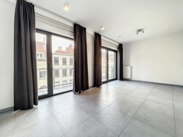 Salon lumineux dappartement moderne avec grandes baies vitrées et carrelage gris   appartement 1 chambre  ixelles