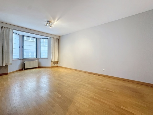 Salon vide lumineux avec parquet grandes fenêtres et radiateur dans appartement   appartement 1 chambre  bruxelles