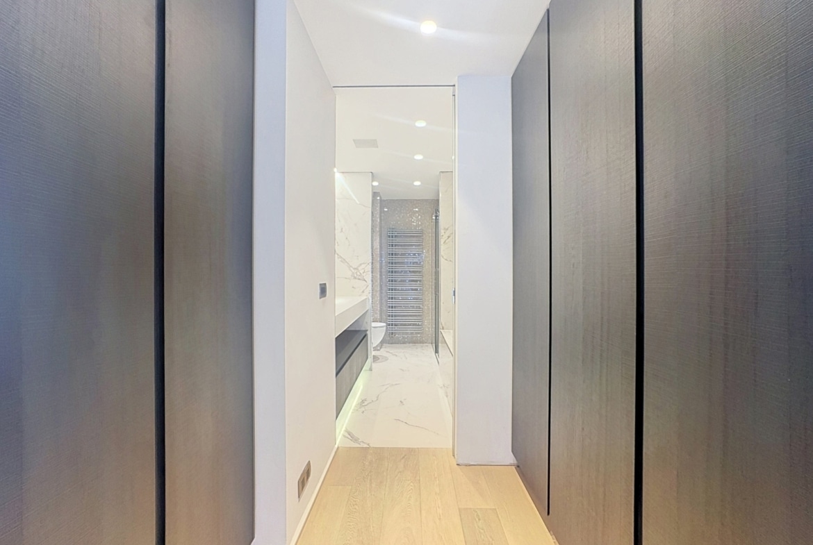 Couloir moderne avec placards menant à une salle de bain luxueuse.