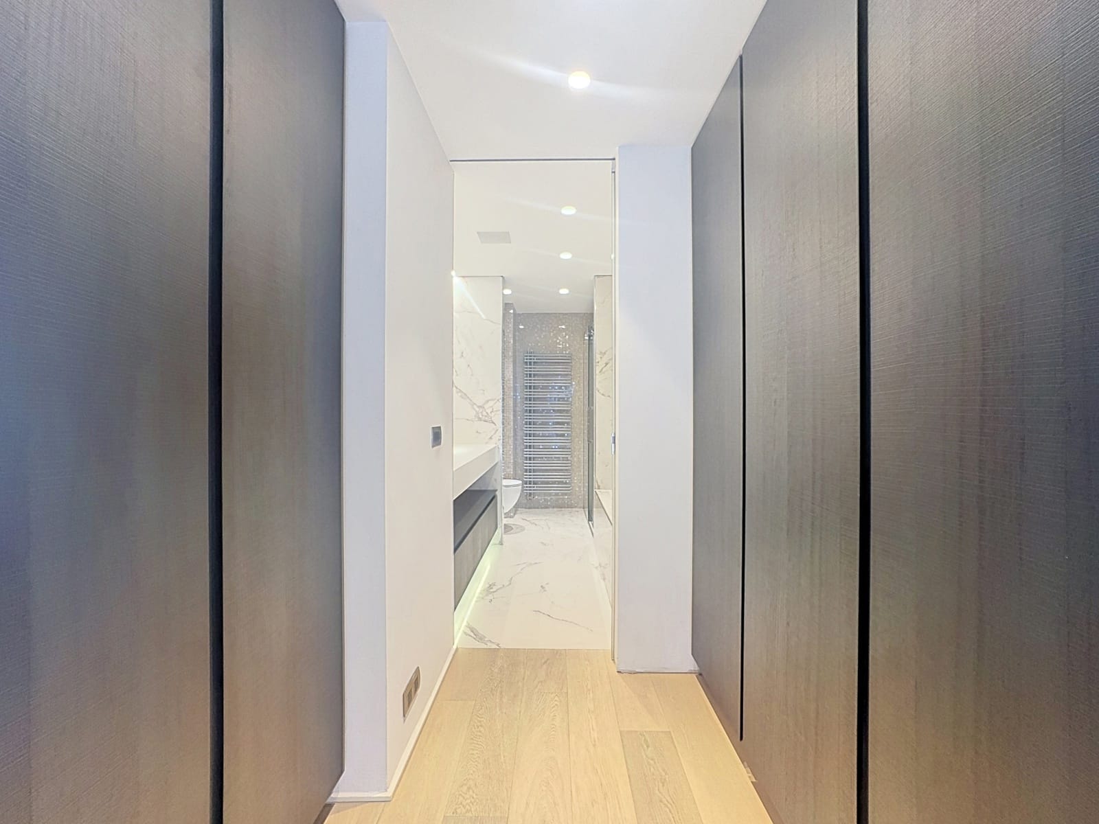Couloir Moderne vers Salle de Bain – You Real Estate Agency Couloir moderne avec placards menant à une salle de bain luxueuse.