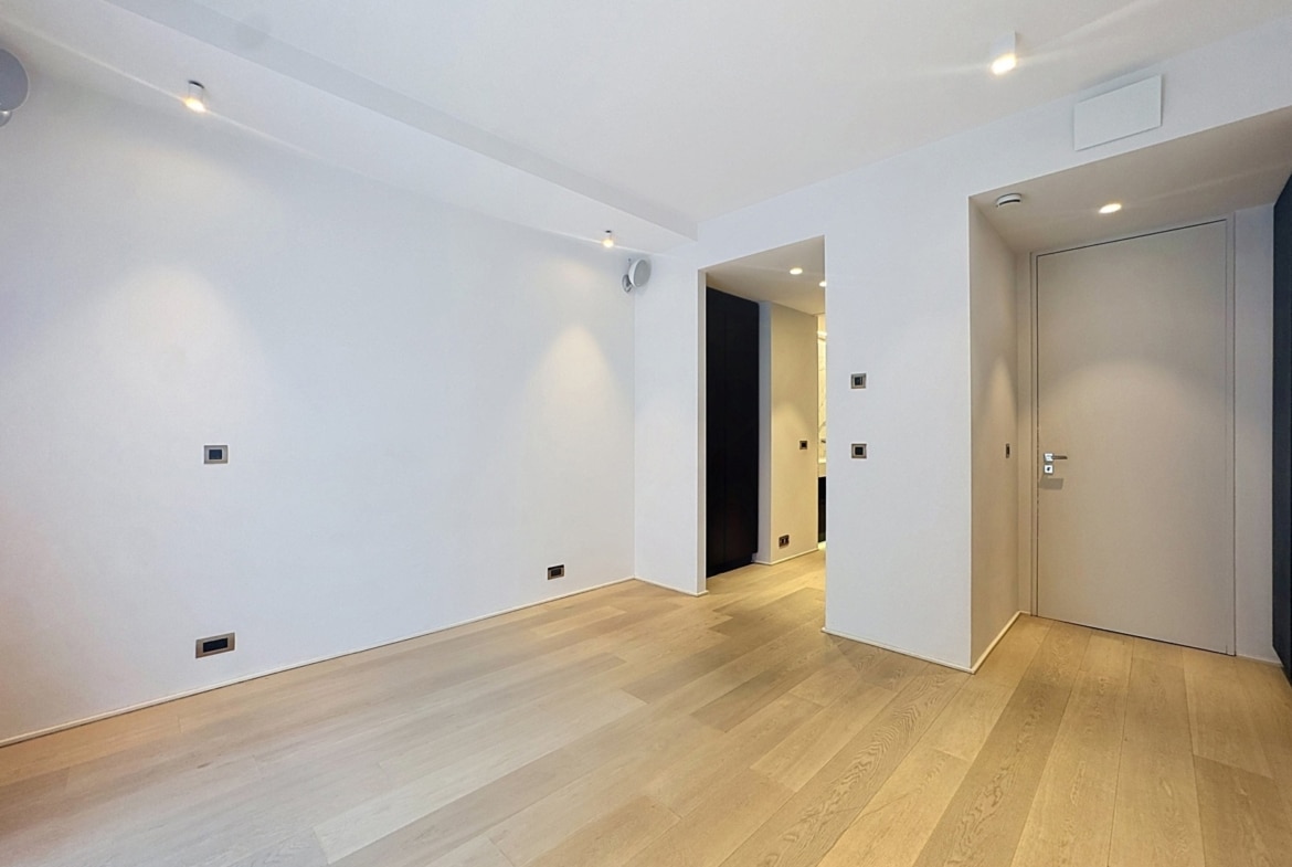 Salon vide d’appartement moderne avec parquet bois et éclairage encastré.