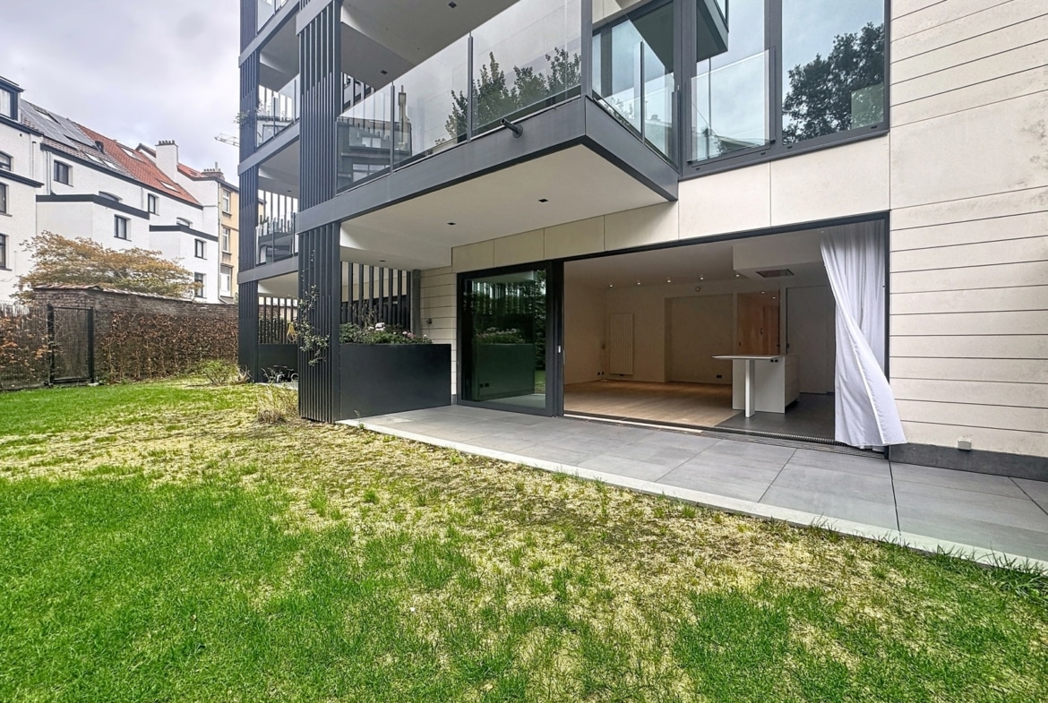 Appartement moderne avec terrasse, jardin privatif et salon ouvert avec cuisine équipée.