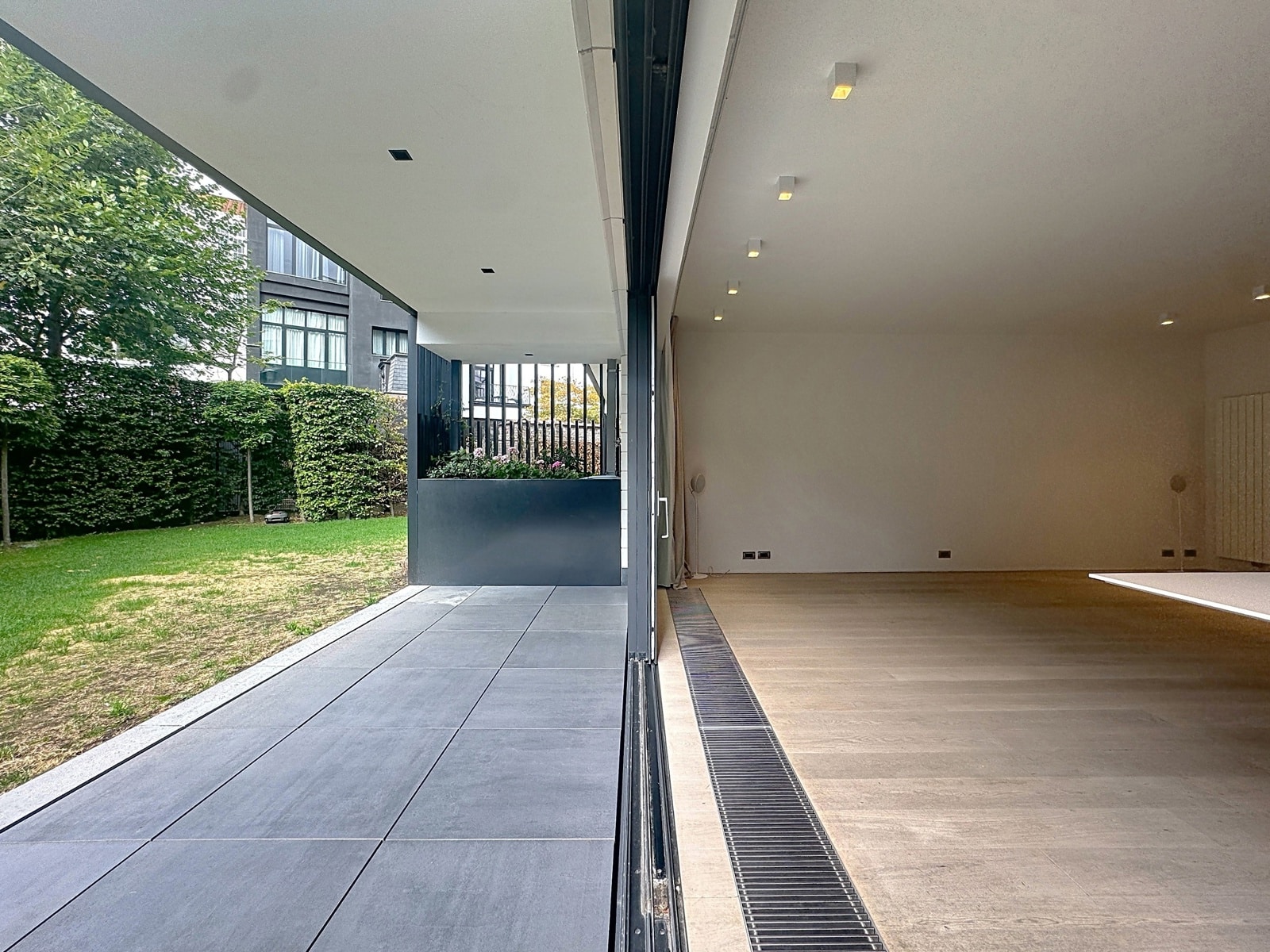 Salon Ouvert sur Terrasse et Jardin – You Real Estate Agency Salon moderne ouvert sur terrasse et jardin verdoyant dans maison contemporaine.