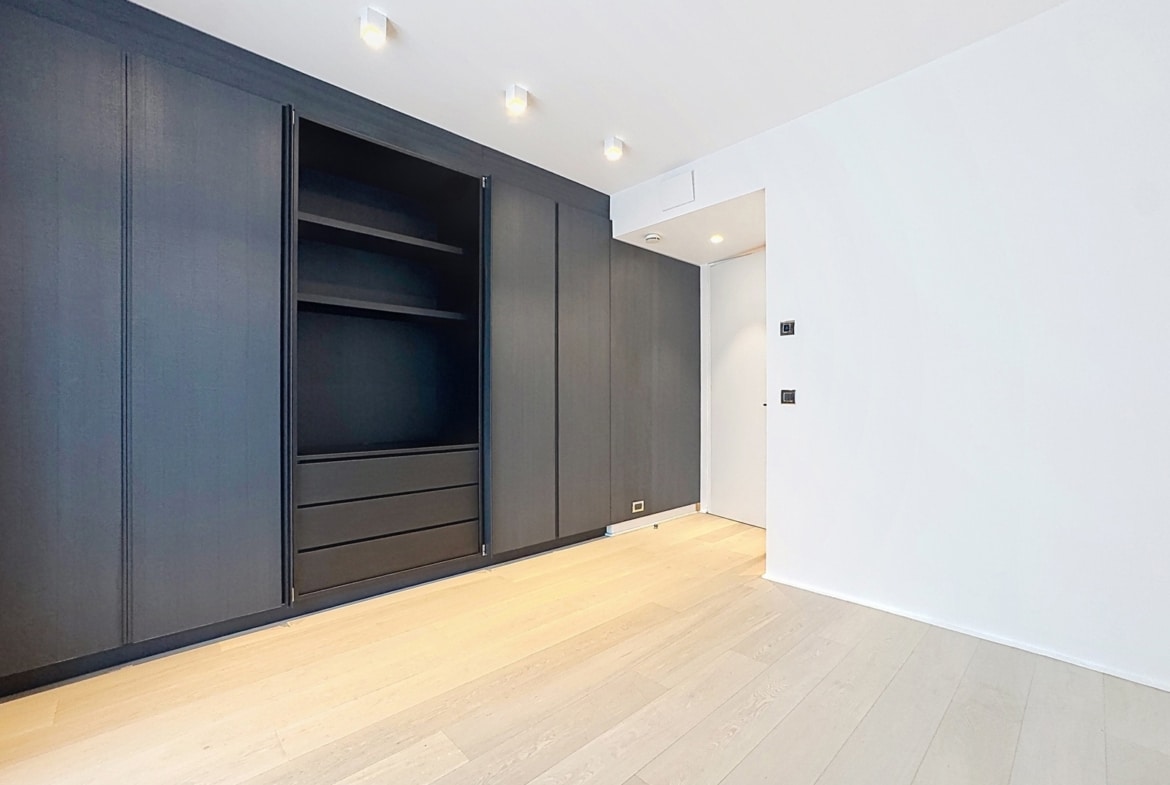 Dressing moderne avec placards intégrés sombres et parquet clair dans appartement.