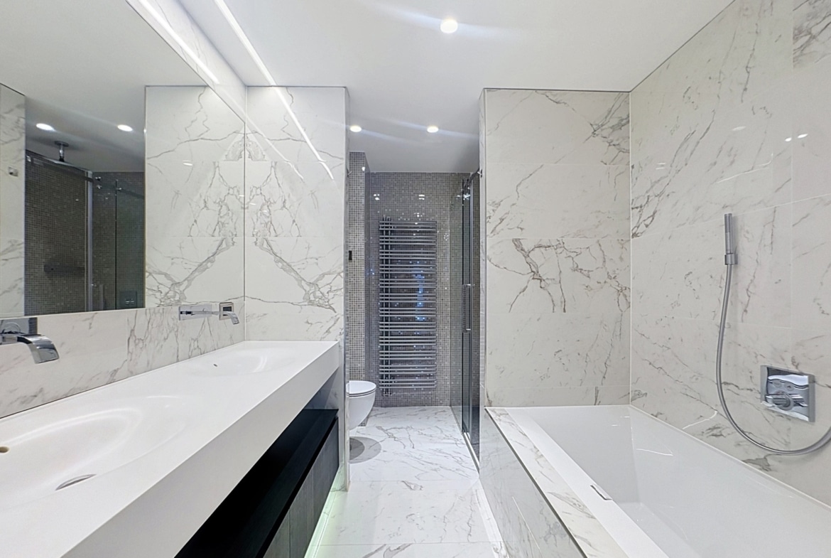 Salle de bains moderne en marbre avec double vasque et baignoire d’appartement.