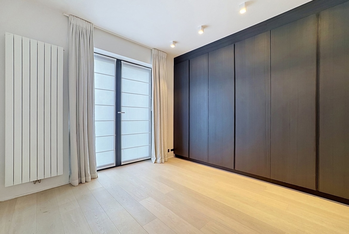 Chambre d’appartement moderne avec dressing intégré, parquet clair et grande baie vitrée.