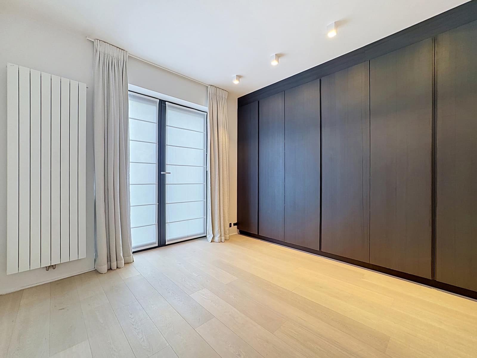 Chambre Moderne Avec Dressing Intégré – You Real Estate Agency Chambre d’appartement moderne avec dressing intégré, parquet clair et grande baie vitrée.