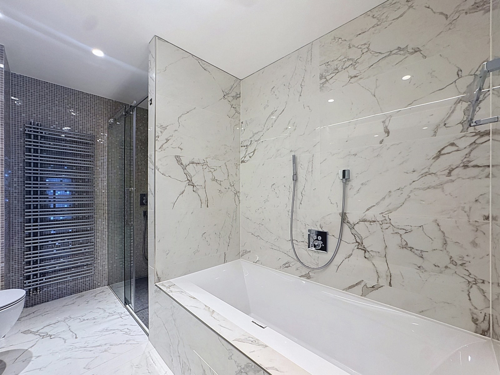 Salle de Bains Luxueuse en Marbre – You Real Estate Agency Salle de bains luxueuse en marbre avec baignoire et douche vitrée dans appartement moderne.