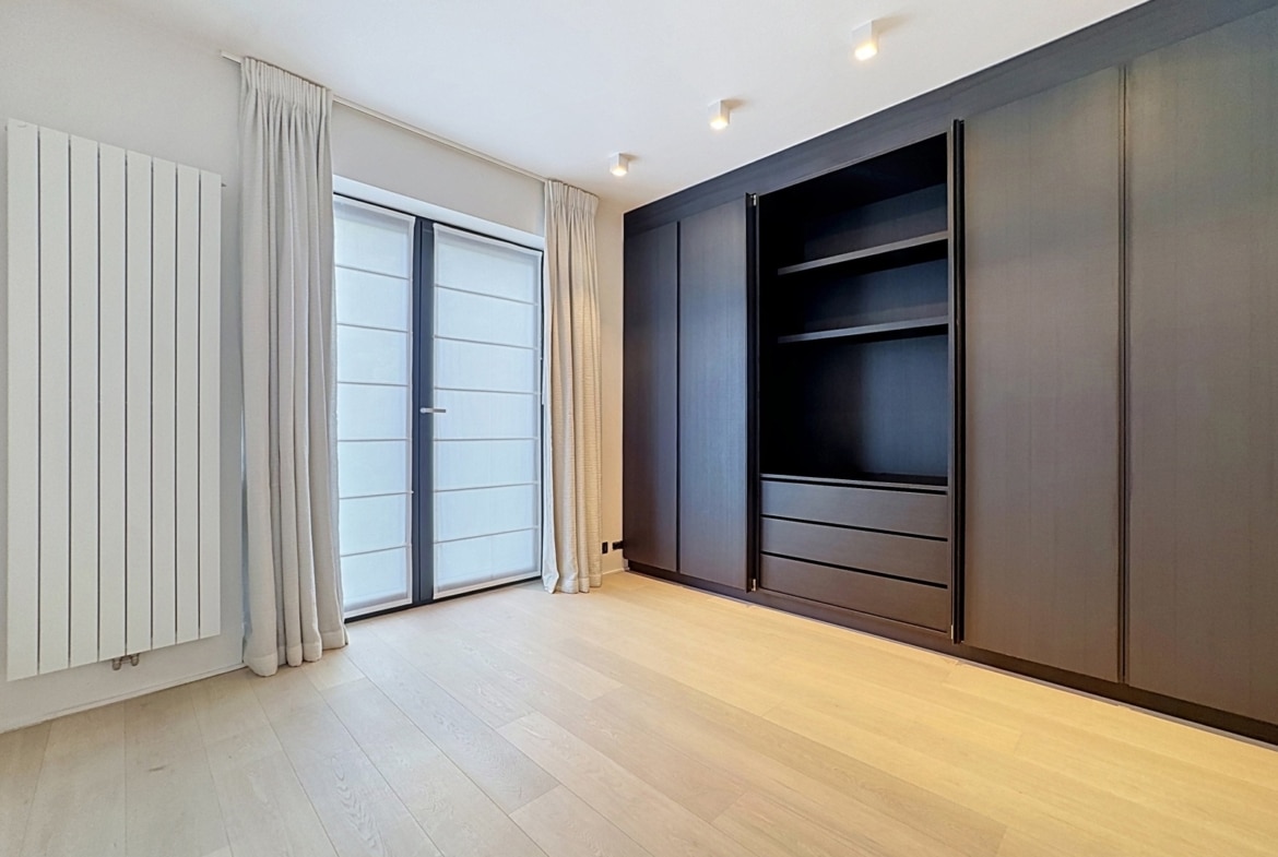 Chambre avec dressing intégré en bois foncé et parquet clair dans appartement moderne.