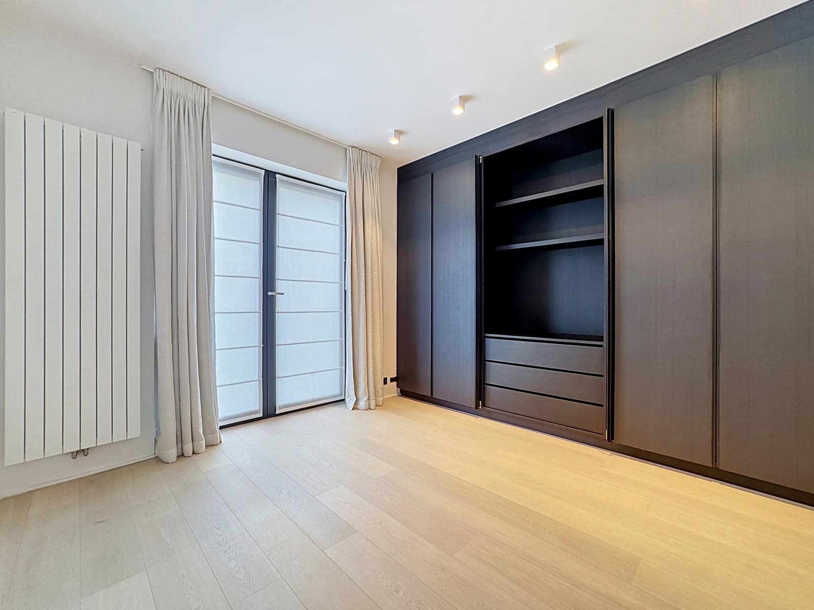 Chambre Moderne Avec Dressing Intégré – You Real Estate Agency Chambre avec dressing intégré en bois foncé et parquet clair dans appartement moderne.