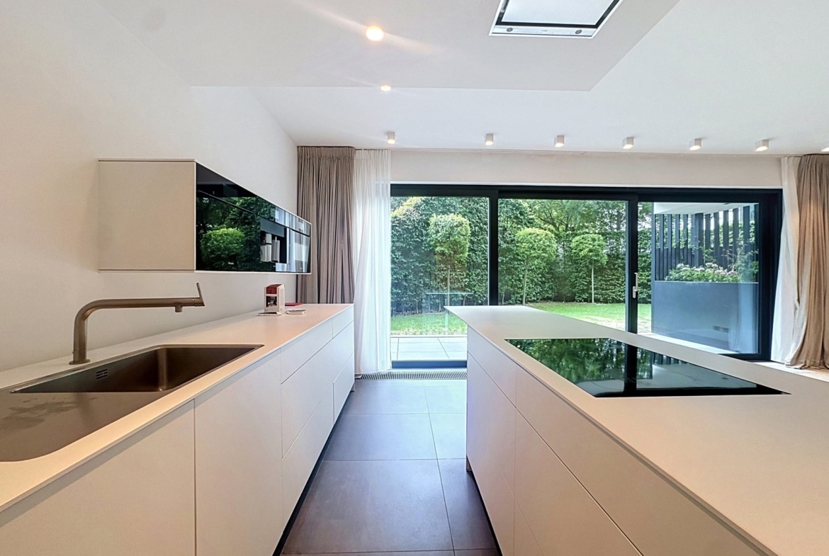Cuisine moderne de maison avec îlot central et vue sur jardin.
