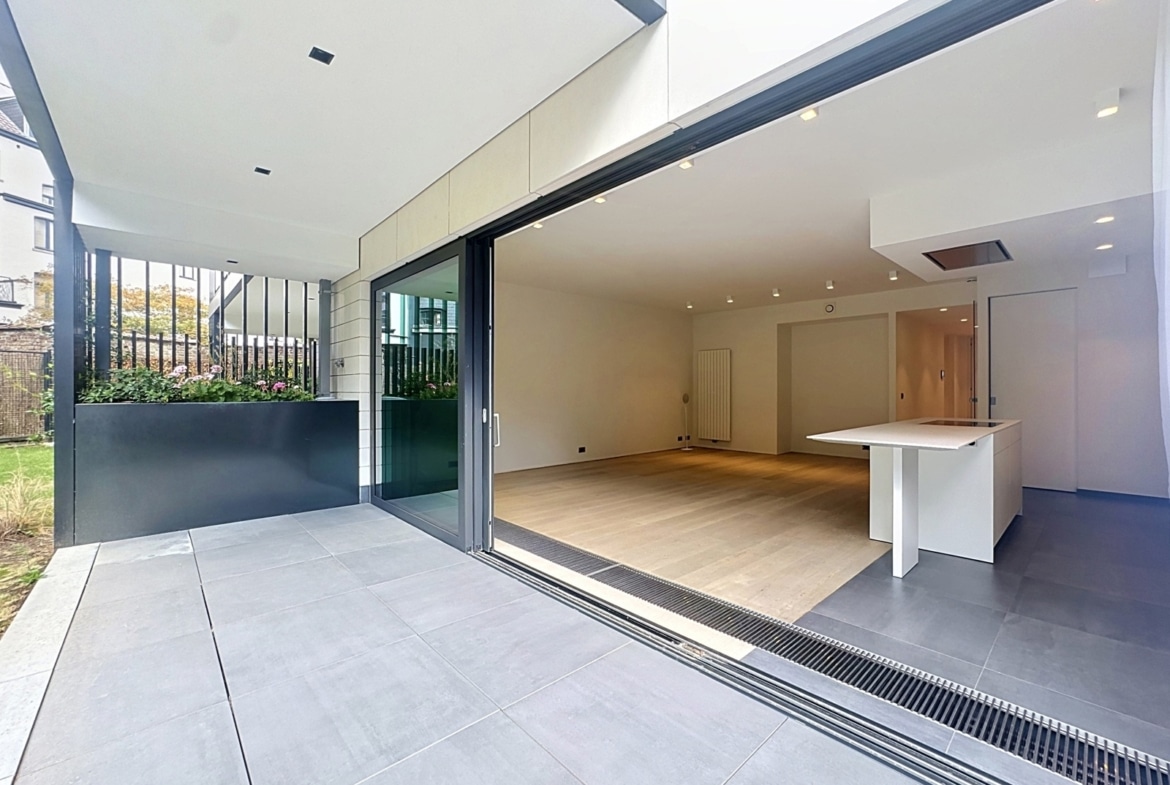 Maison moderne avec terrasse, cuisine ouverte et salon lumineux.