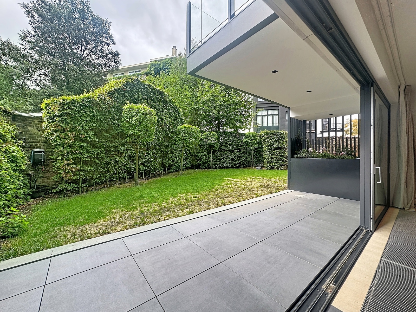Terrasse Moderne avec Jardin Paysager – You Real Estate Agency Terrasse moderne avec jardin paysager et baie vitrée d’une maison contemporaine.