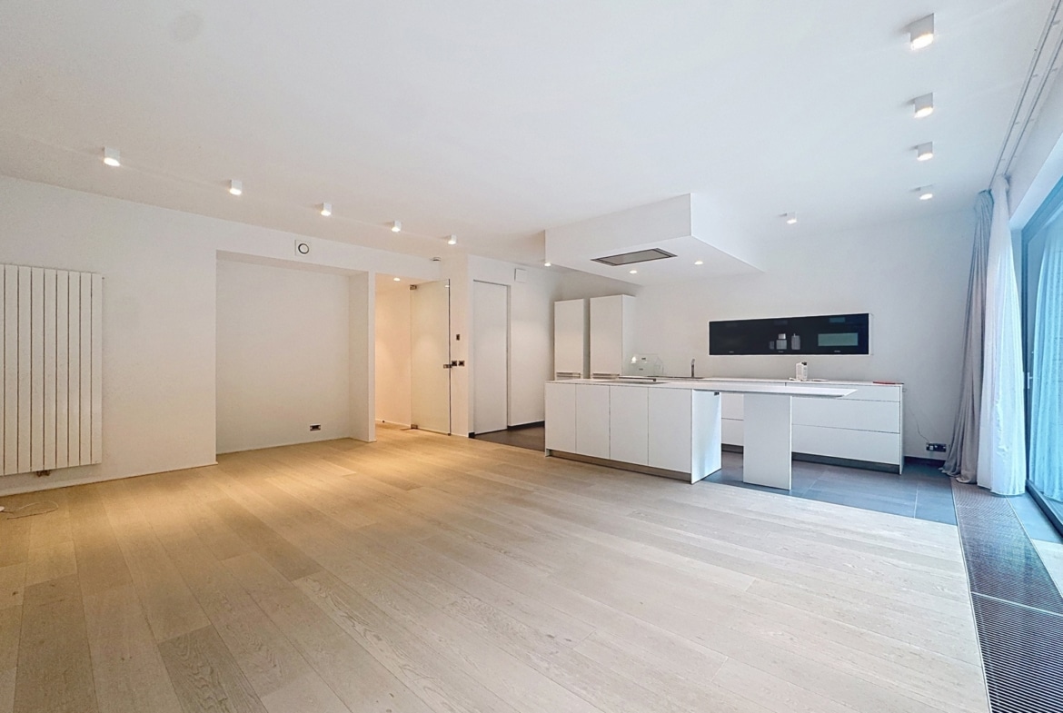 Open-plan kitchen with white cabinets and island, large windows with sheer curtains, light wood floors menacing natural lighted space