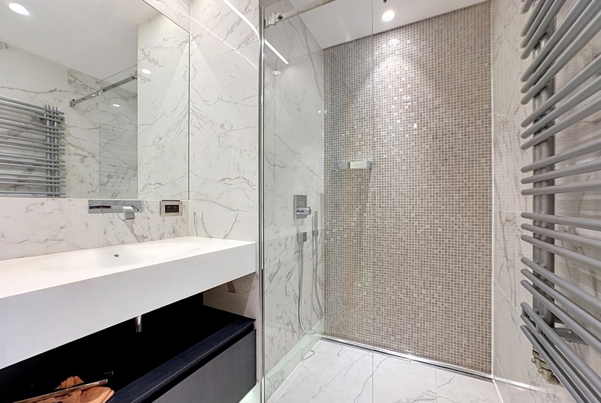 Salle de bain moderne en marbre avec douche vitrée pour appartement.