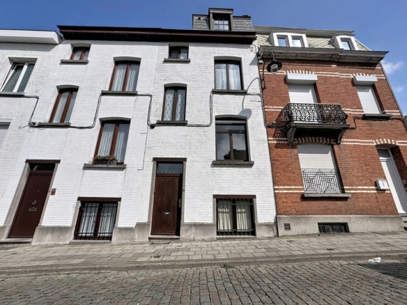 Row of white and red brick townhouses with tall brown doors and large windows on a cobblestone street under a blue sky featuring a wrought iron balcony on the red brick building   maison 3 chambres  bruxelles