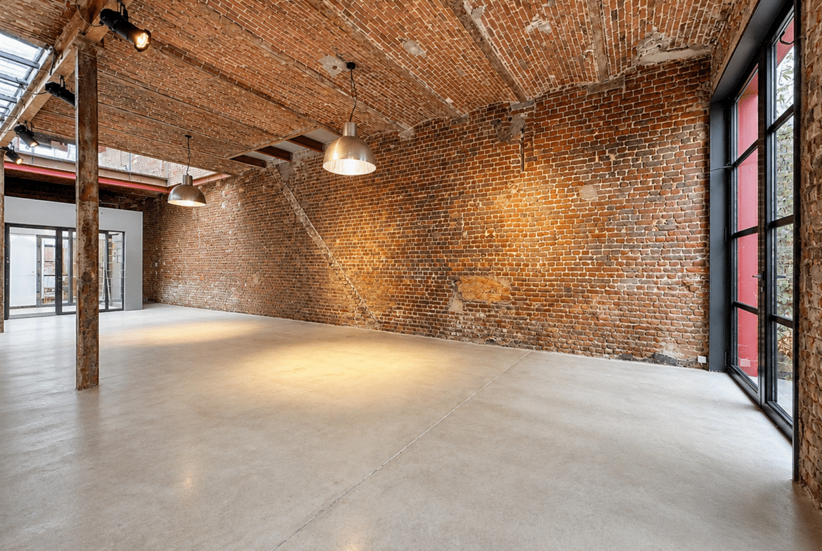 Loft industriel rénové avec voûtes en briques apparentes et grandes fenêtres.