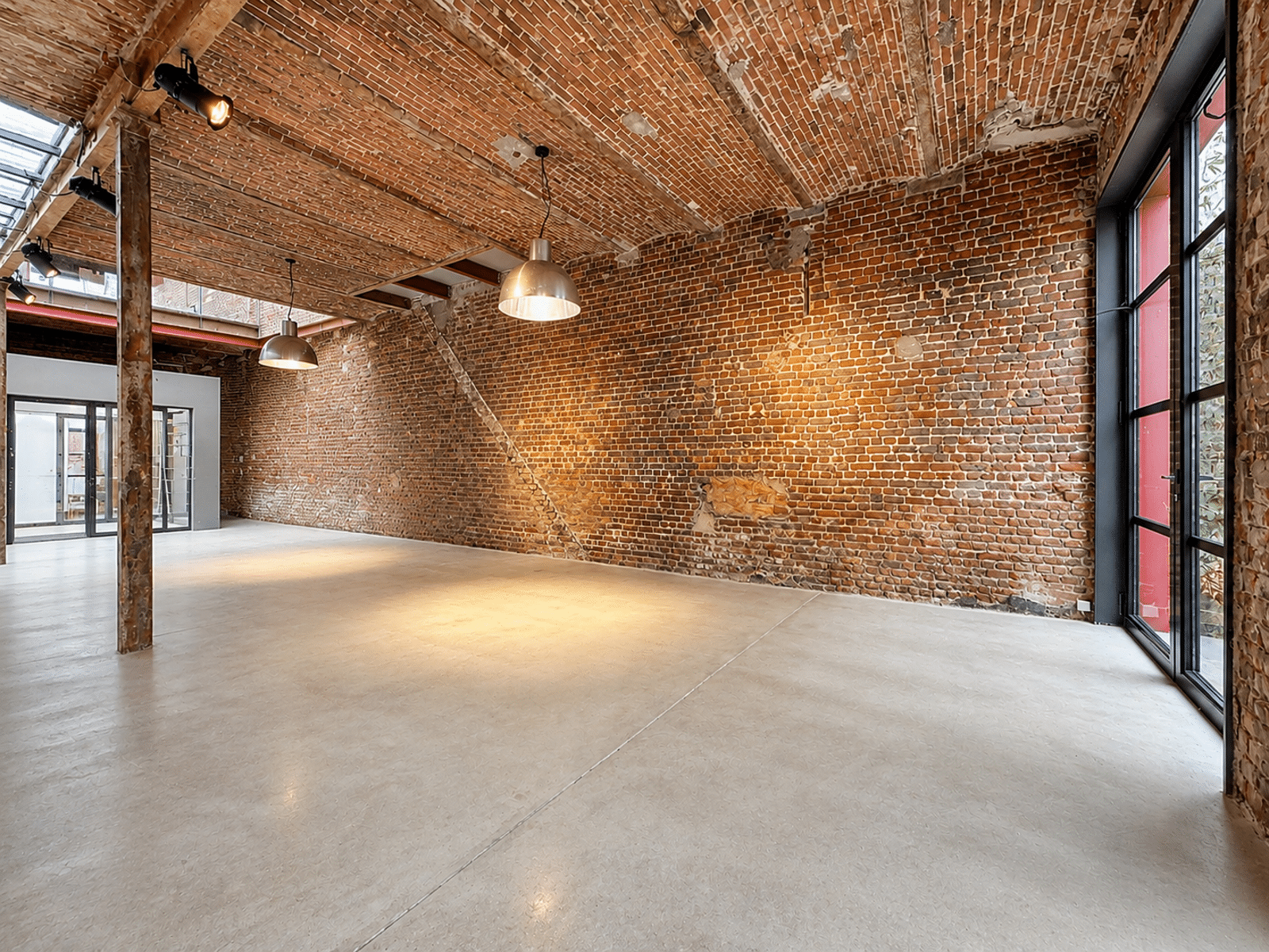Espace Loft Industriel Rénové – You Real Estate Agency Loft industriel rénové avec voûtes en briques apparentes et grandes fenêtres.