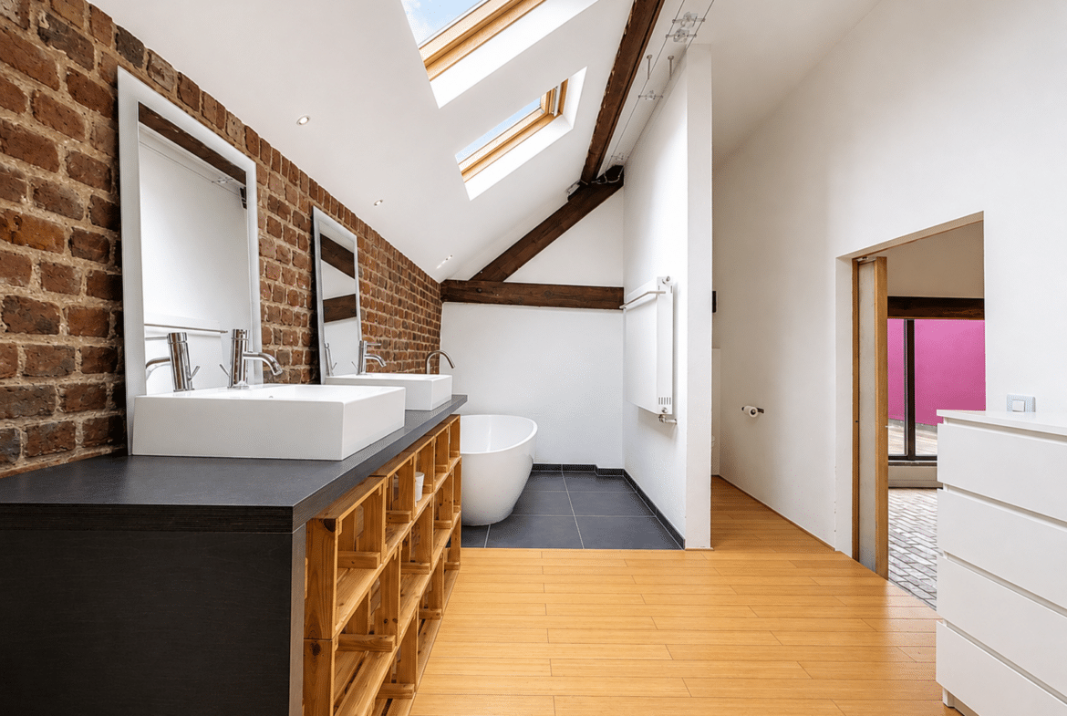 Salle de bains moderne d’appartement sous combles avec baignoire et double vasque.