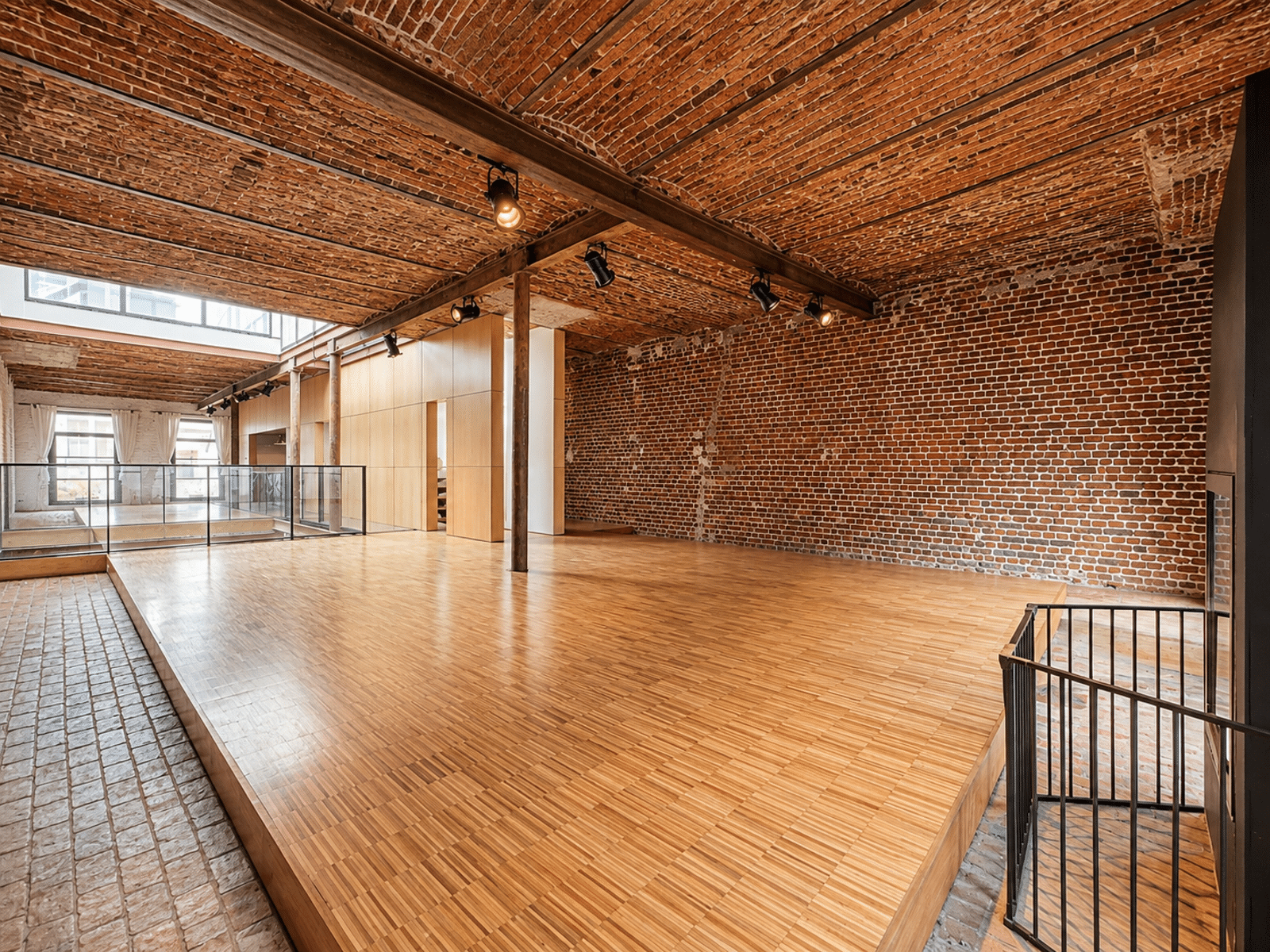 Espace Loft Rénové en Briques – You Real Estate Agency Appartement loft rénové avec murs en briques, plafond voûté et plancher bois.