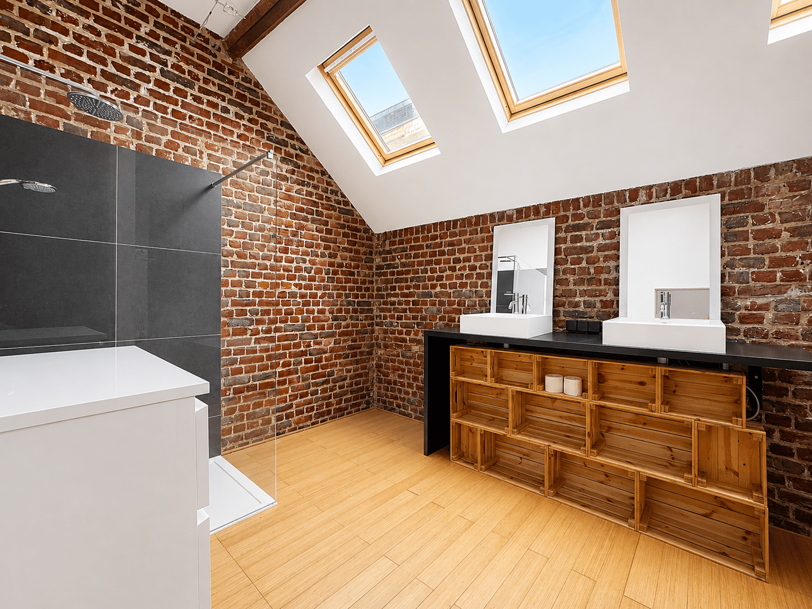 Salle de Bain Moderne sous Combles – You Real Estate Agency Salle de bain moderne sous combles avec briques apparentes et puits de lumière.