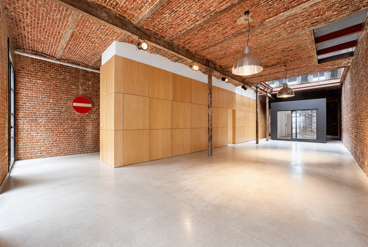 Appartement loft industriel avec murs en briques, plafond voûté et grande pièce ouverte.