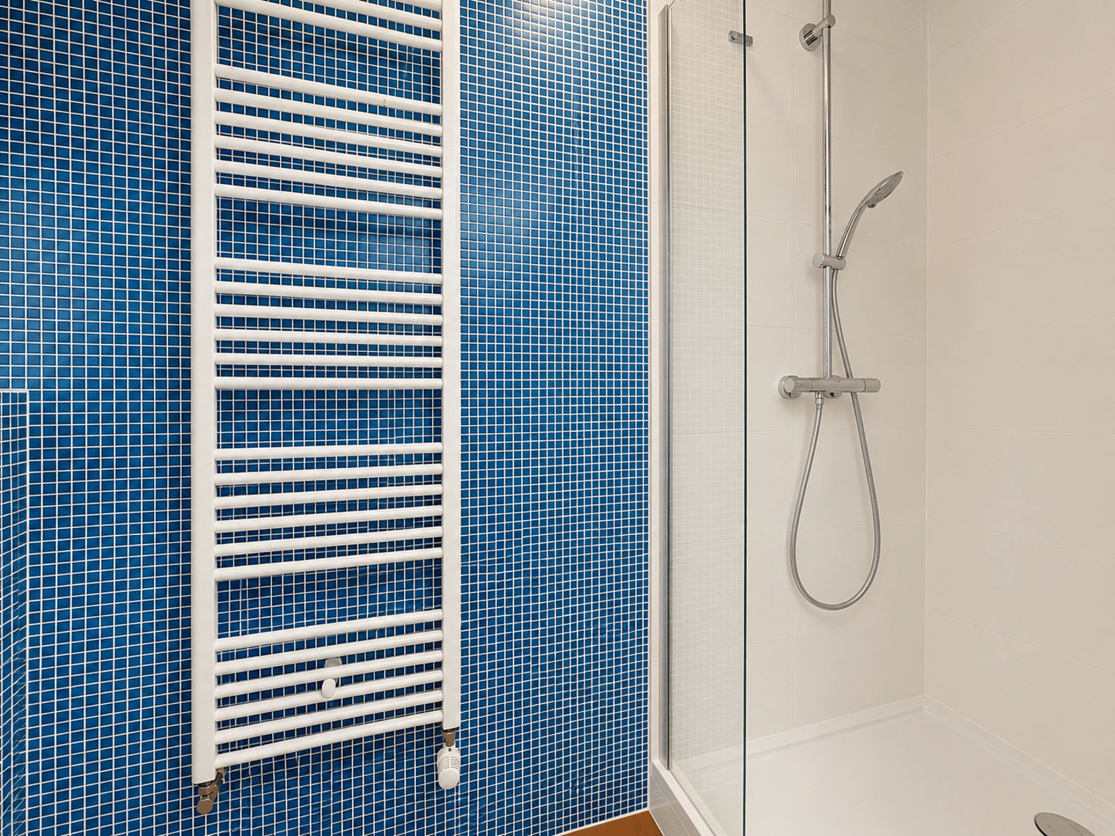 Salle de Bain Moderne avec Douche – You Real Estate Agency Salle de bain moderne d’appartement avec douche vitrée et carrelage bleu.