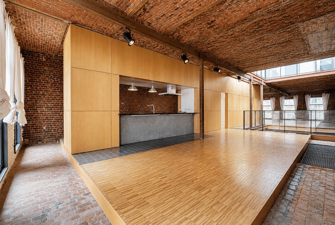 Appartement loft avec cuisine ouverte, plafond voûté en briques et poutres apparentes.