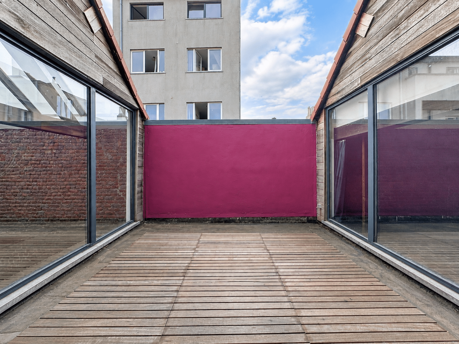 Terrasse Intérieure Moderne – You Real Estate Agency Terrasse intérieure moderne avec bardage bois, baies vitrées et mur rose.